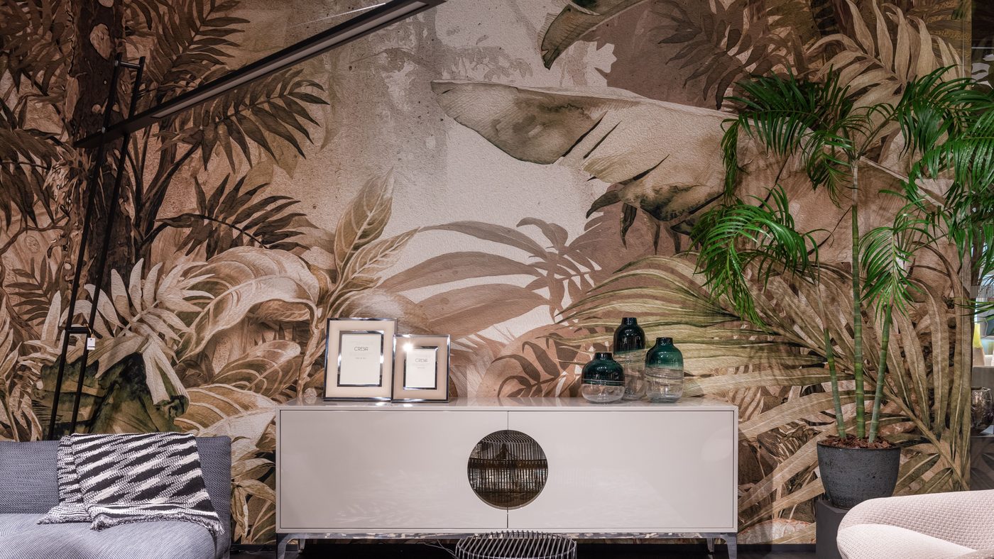Living room with a large botanical mural wallpaper in sepia and sage tones behind a pale lacquered sideboard