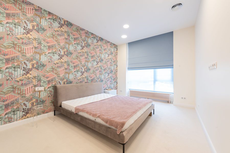 Minimal modern bedroom with a full-height illustrated pagoda-pattern wallpaper on the wall behind a low upholstered bed