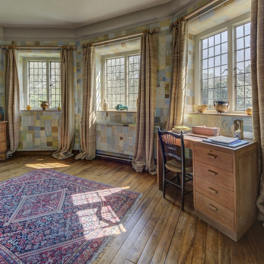 Home study with soft patchwork-patterned walls, leaded windows, linen curtains, an oak desk and a traditional rug